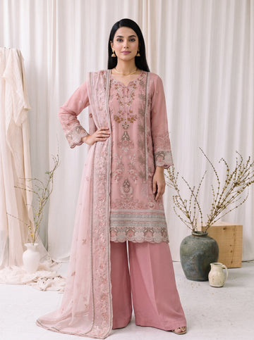 Woman wearing a pink embroidered traditional outfit with a matching dupatta in a minimalistic setting.